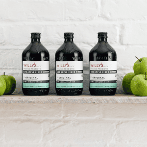 Willys Organic Live Apple Cider Vinegar bottles with fresh green apples.